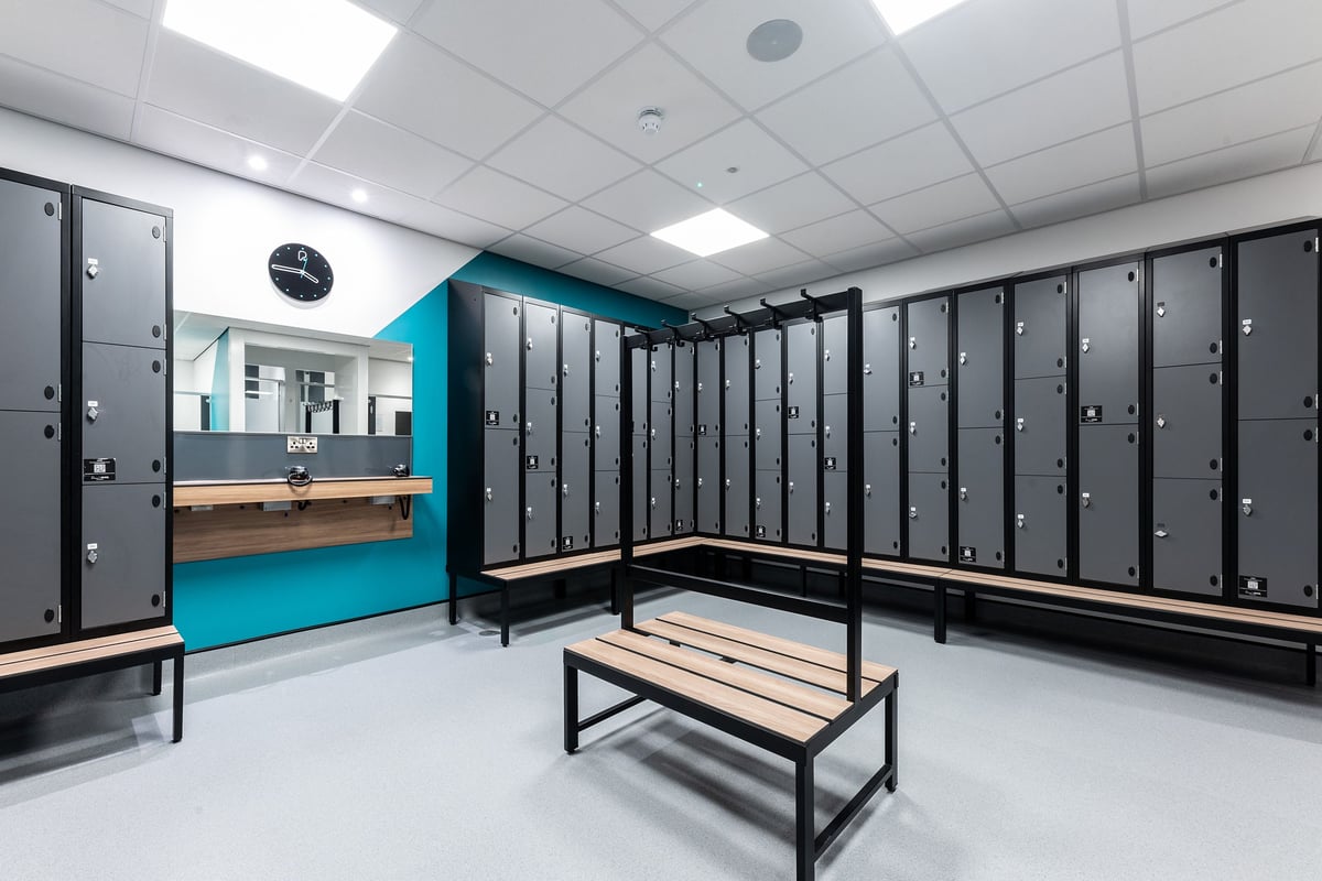 PureGym Dumfries: Rows of lockers, benches, and blue accents in what appears to be a changing room area.