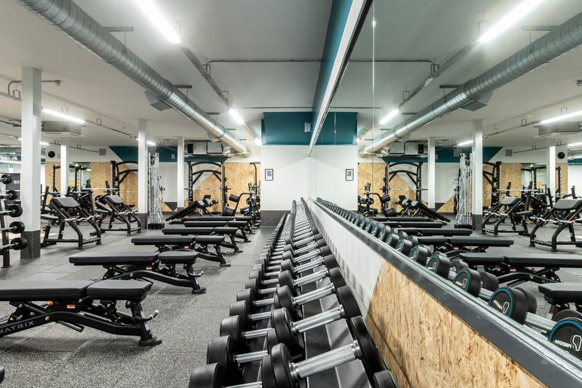 PureGym Macclesfield Silk Road: Rows of benches, weight racks, free weights, and mirrored walls in a modern gym setting.