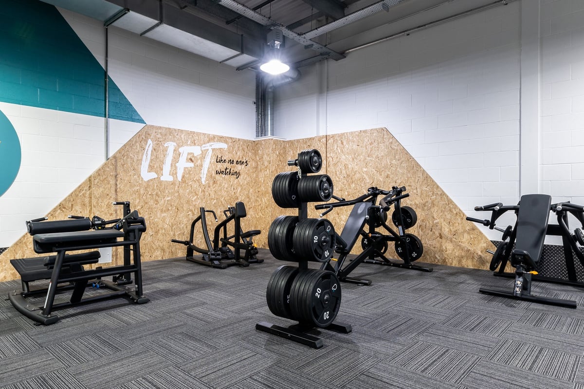 PureGym Nottingham Beeston: Free weights, weight racks, benches, and patterned rubber flooring in a fitness studio space.