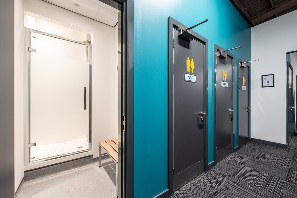 PureGym Alfreton: Changing rooms with teal and grey lockers, benches, and an entry door.