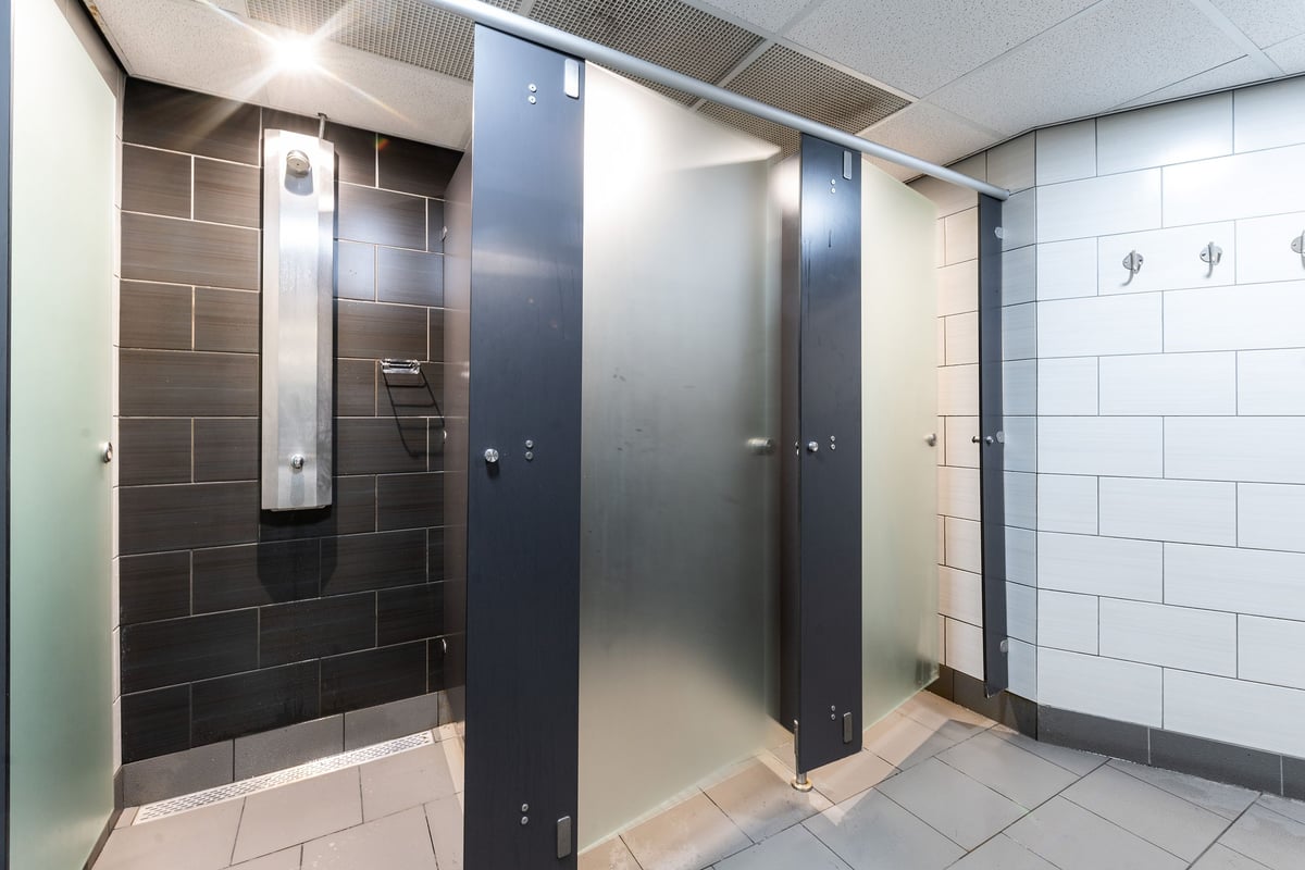 PureGym Aintree: Rows of lockers, bathroom stalls, and tiled shower area inside changing rooms.