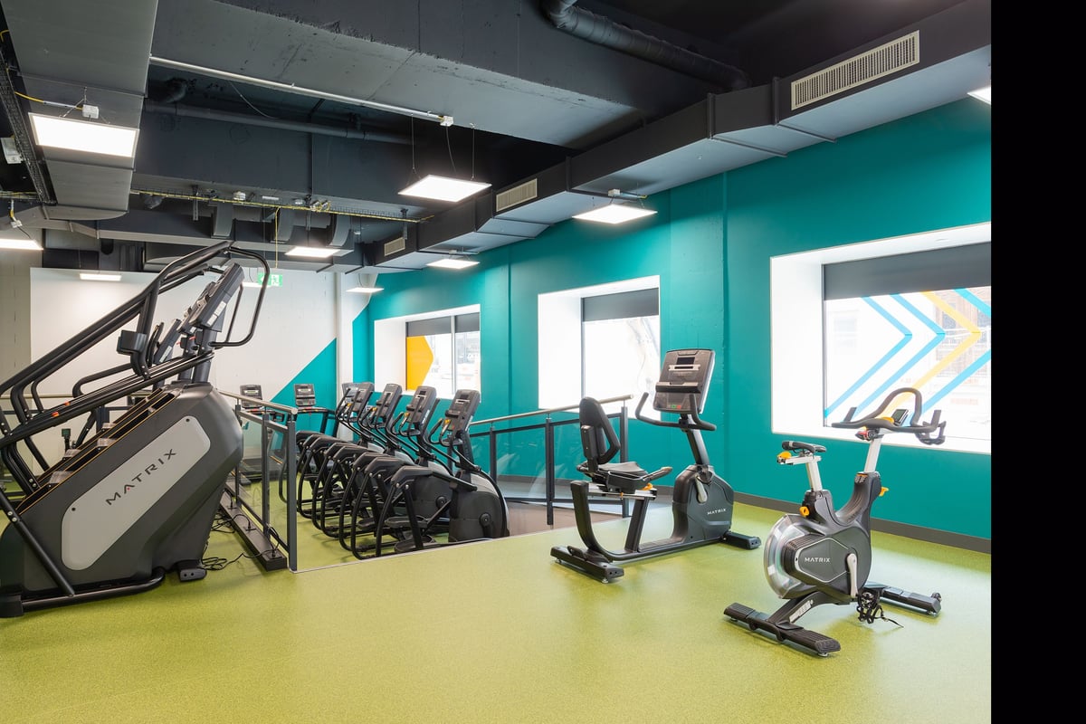 PureGym La Chaux-de-fonds: Fitness studio with treadmills, exercise bikes, weights, and teal accent walls.