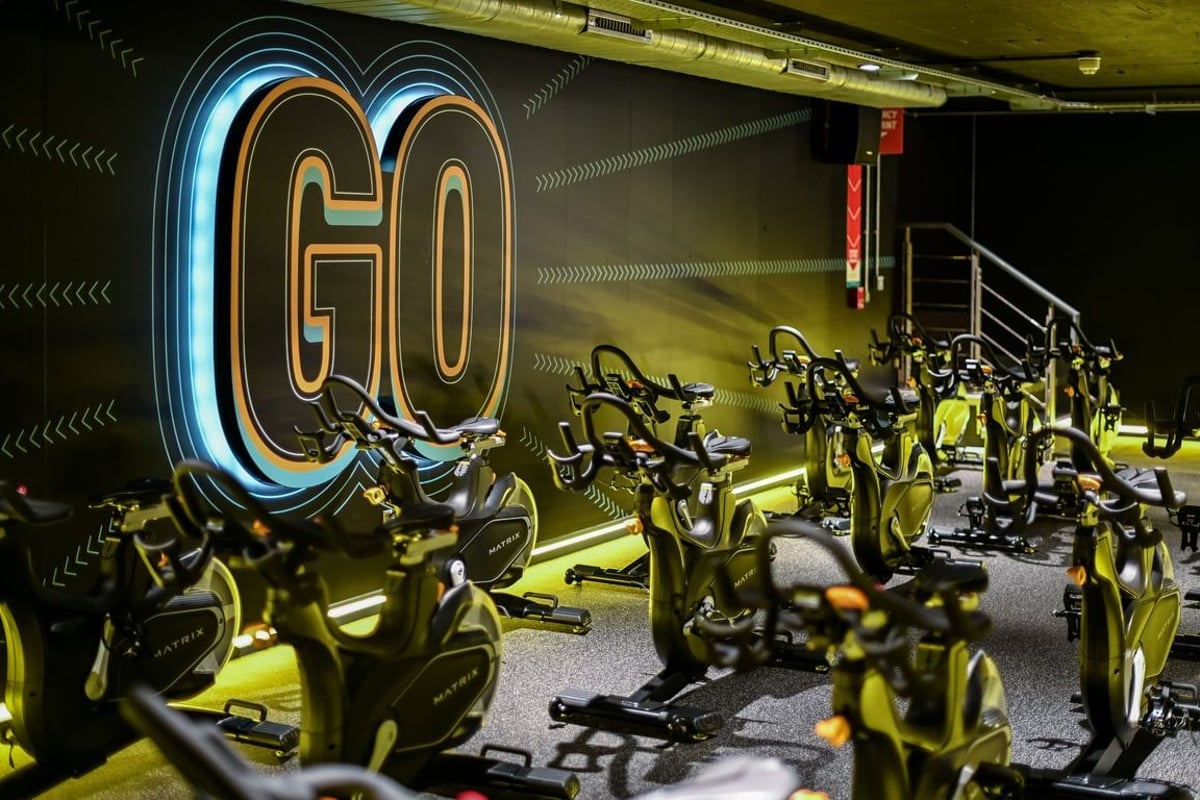 PureGym London Piccadilly: Rows of stationary bikes, neon "GO" signage, industrial lighting and design aesthetic.