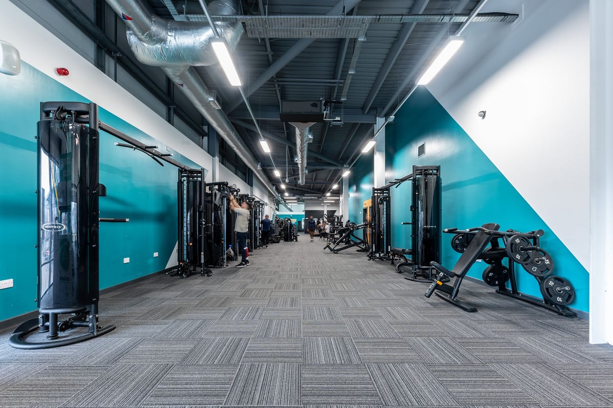 PureGym Chatham: Weight racks, resistance machines, rubberised flooring, and teal walls in a modern gym interior.
