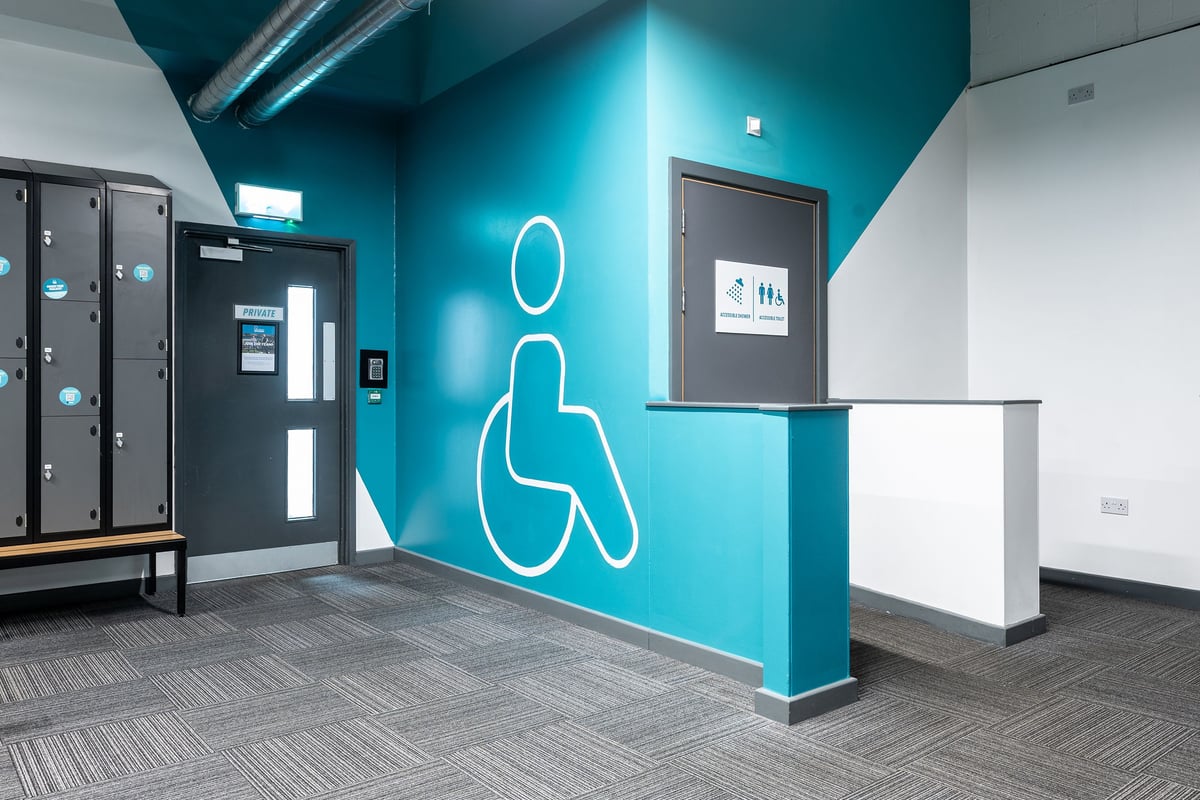 PureGym York: Brilliant blue-lit studio with abstract human outline, self-service kiosks, and digital signage.