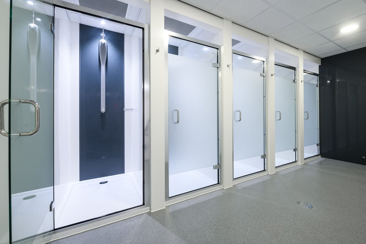 PureGym Birmingham Arcadian Centre: Rows of shower cubicles with frosted glass doors and tiled walls.