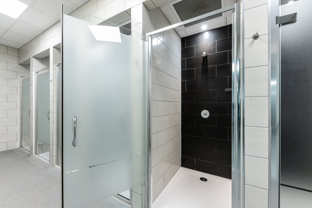 PureGym Newcastle Eldon Garden: Glass shower stalls, tiled walls, and frosted glass doors typical of gym changing rooms.