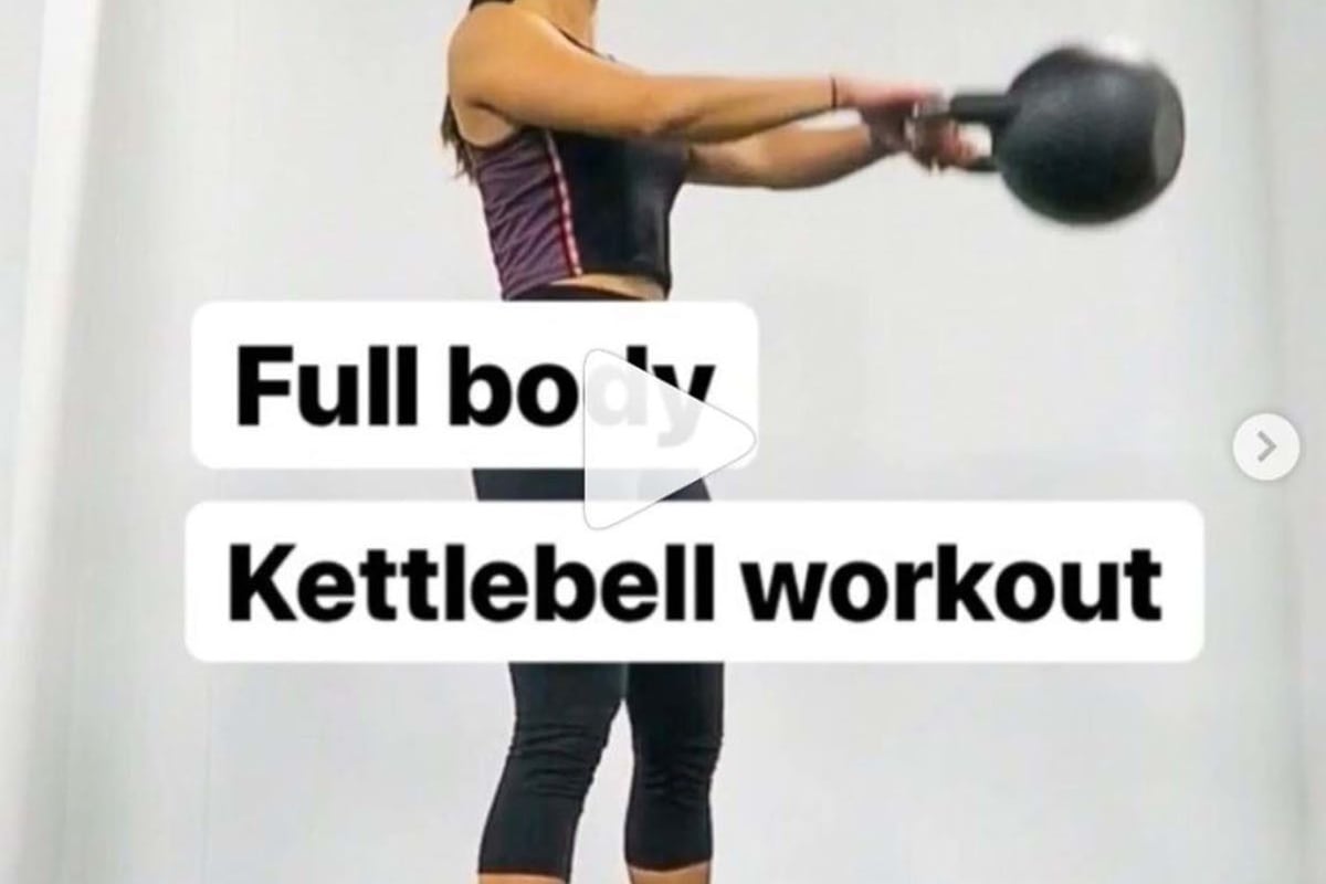Woman swinging a kettlebell in a gym with white walls and grey floor