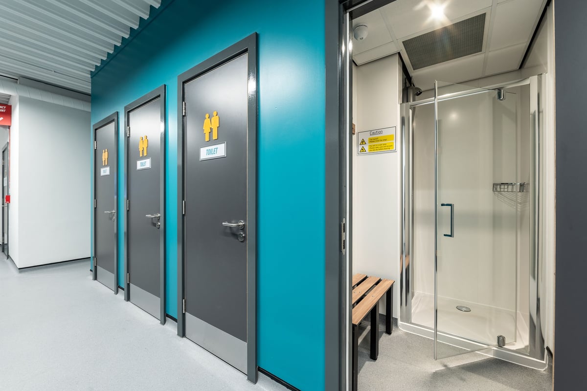 PureGym Brentwood: Changing rooms with full-length mirrors, benches, and metal doors.