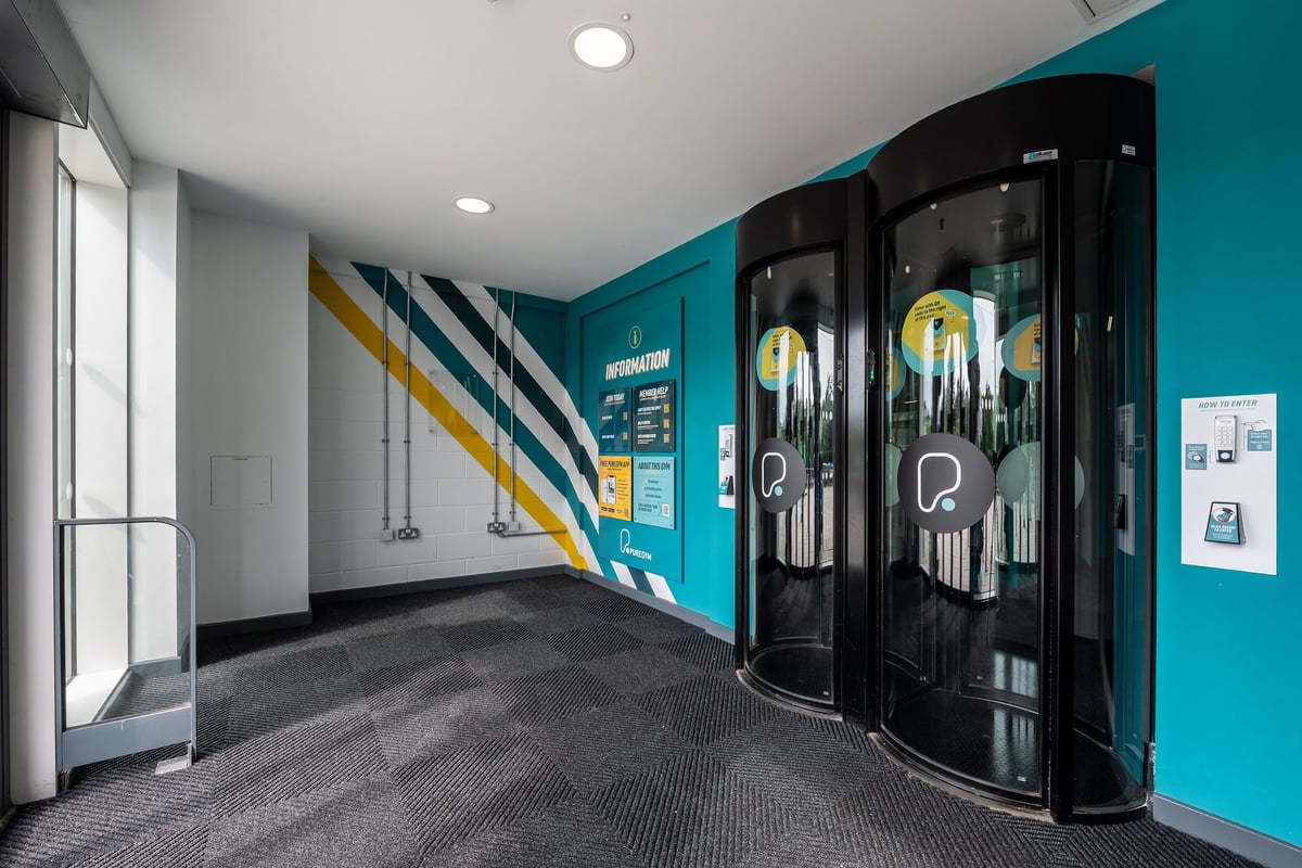 PureGym Wirral Bidston Moss: Gym foyer with teal accent walls and entrance pods.