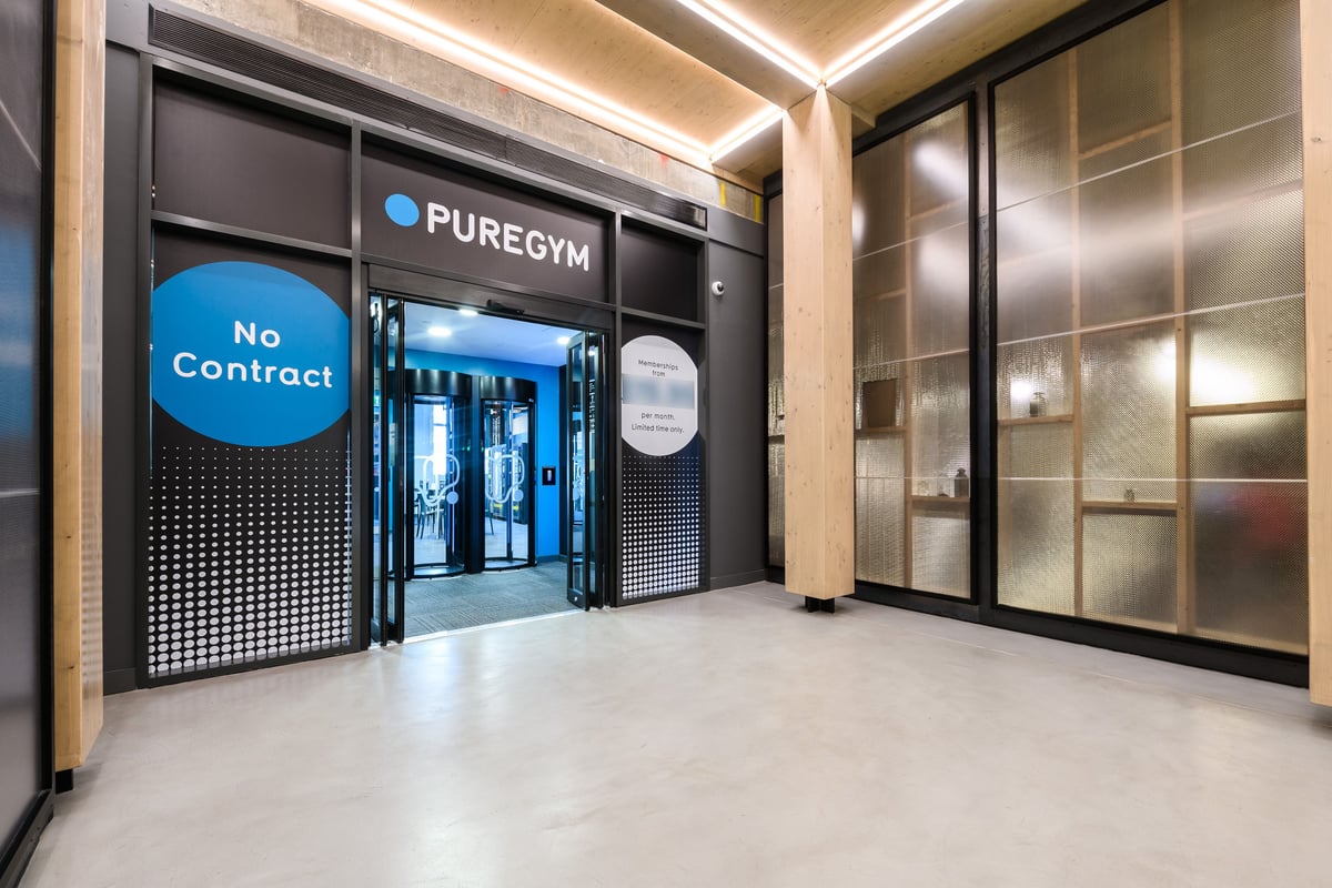 PureGym London East India Dock: Entrance to the gym with no contract required, featuring blue branding and lighting.