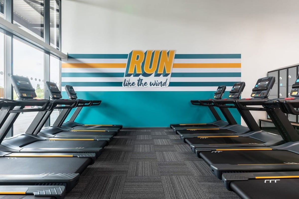 PureGym Nottingham Colwick: Rows of treadmills with motivational wall mural behind them in a gym setting.