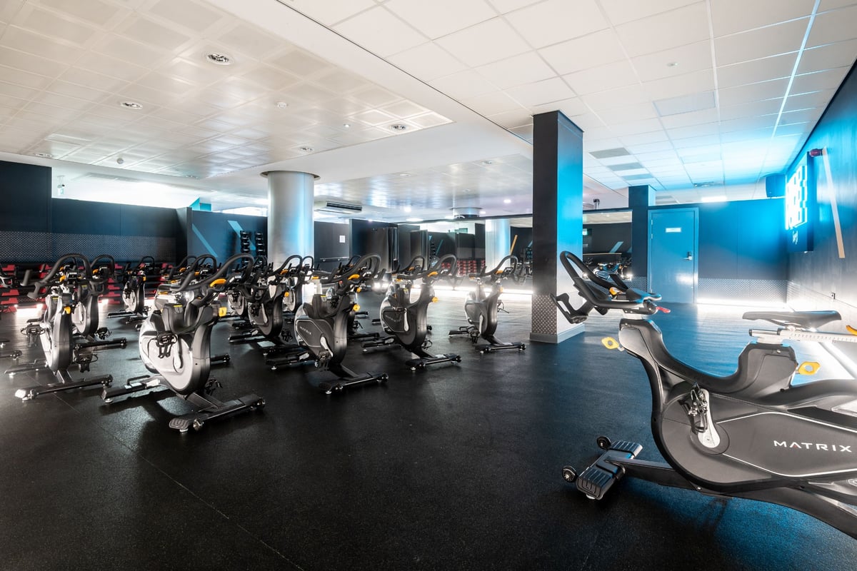 PureGym Edinburgh Exchange Crescent: Indoor gym with rows of stationary bikes, teal accents, and bright lighting.