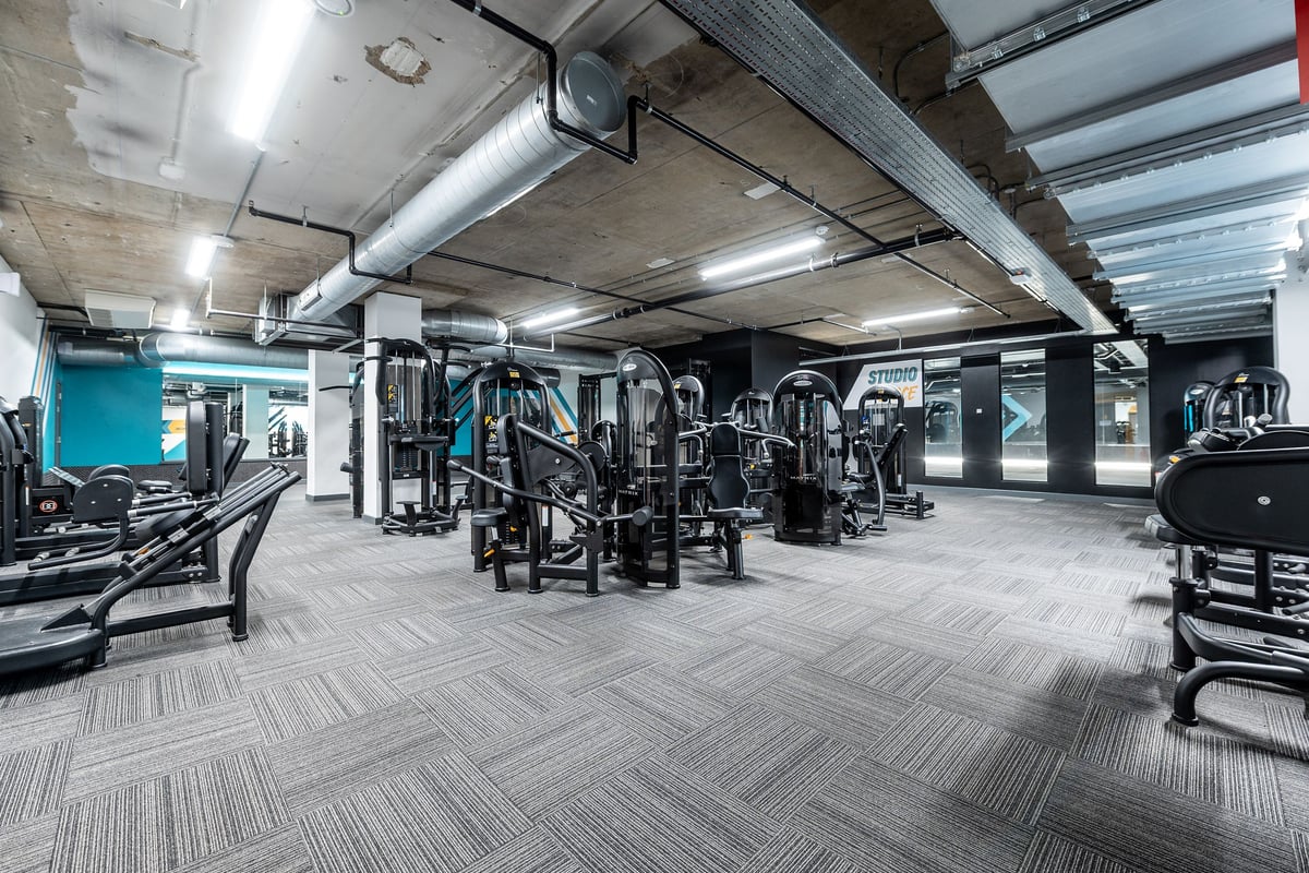 PureGym London Swiss Cottage: Gym interior with weight machines, free weights, benches, and rubberized patterned flooring.