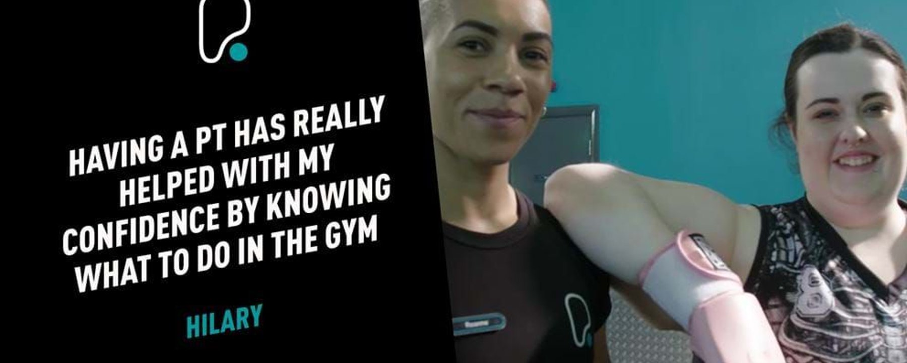 Two women smiling in a gym, one wearing pink boxing gloves and sportswear.