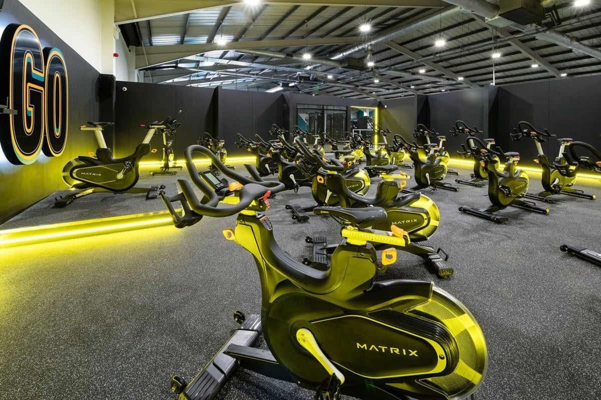 PureGym Leeds Bramley: Rows of yellow stationary bikes with "GO" emblazoned, in a dimly lit fitness studio.