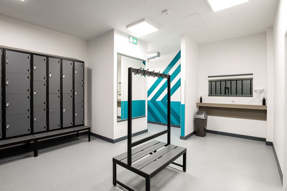 PureGym Lausanne Prilly: Changing room with lockers, benches, access gate, and modern geometric artwork on the wall.