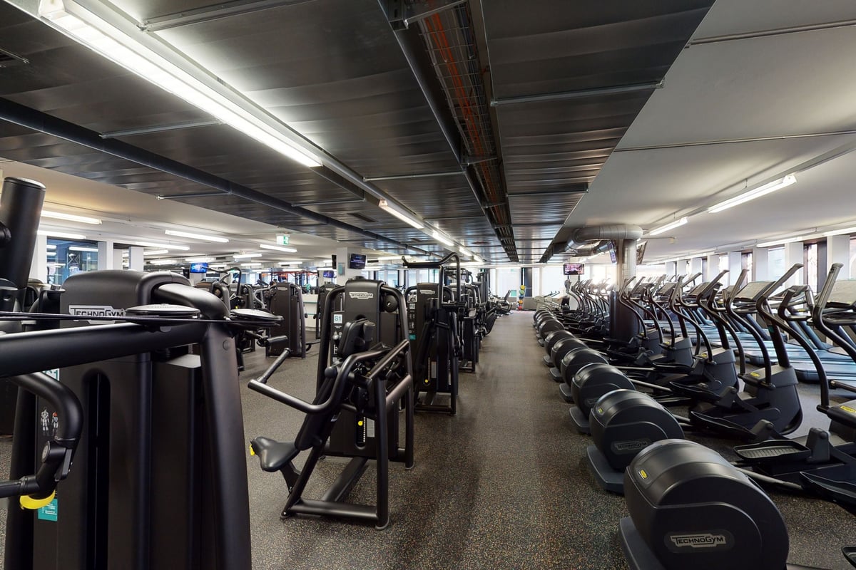 PureGym Basel Clara Huus: Reihen von Laufbändern, Crosstrainern und Kraftgeräten.