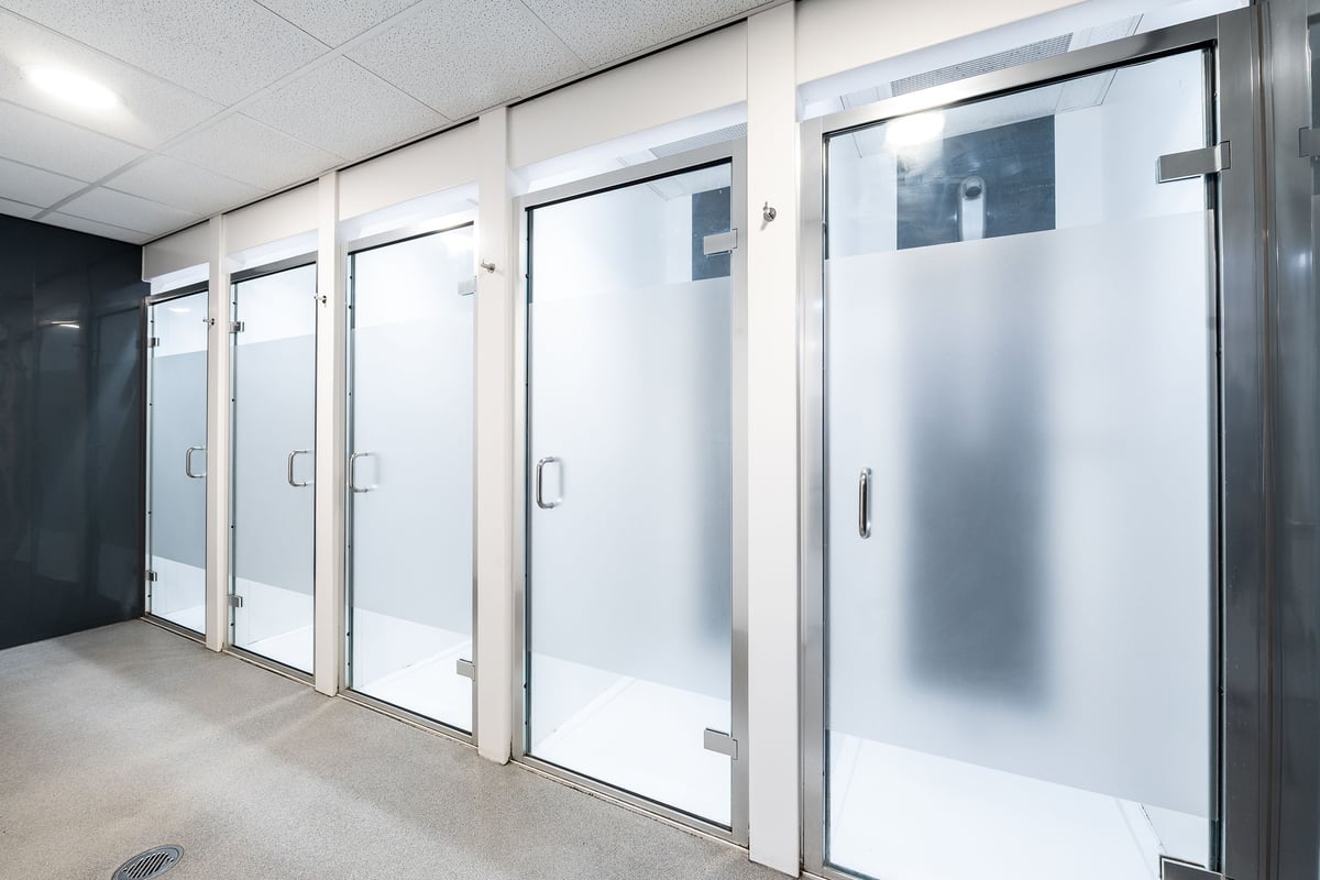 PureGym Norwich Castle Mall: Shower stalls with frosted glass doors.