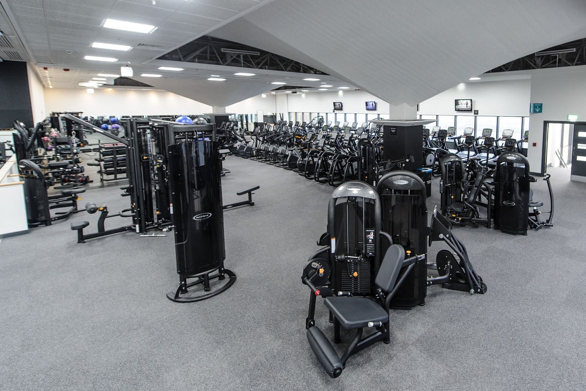 PureGym Bedford Heights: Strength training machines, free weights, benches and rubberized flooring in a gymnasium setting.