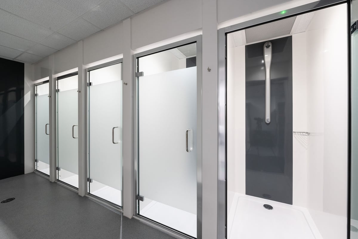 PureGym Andover: Glass shower stalls and privacy curtains, typical of a gym's changing room facilities.