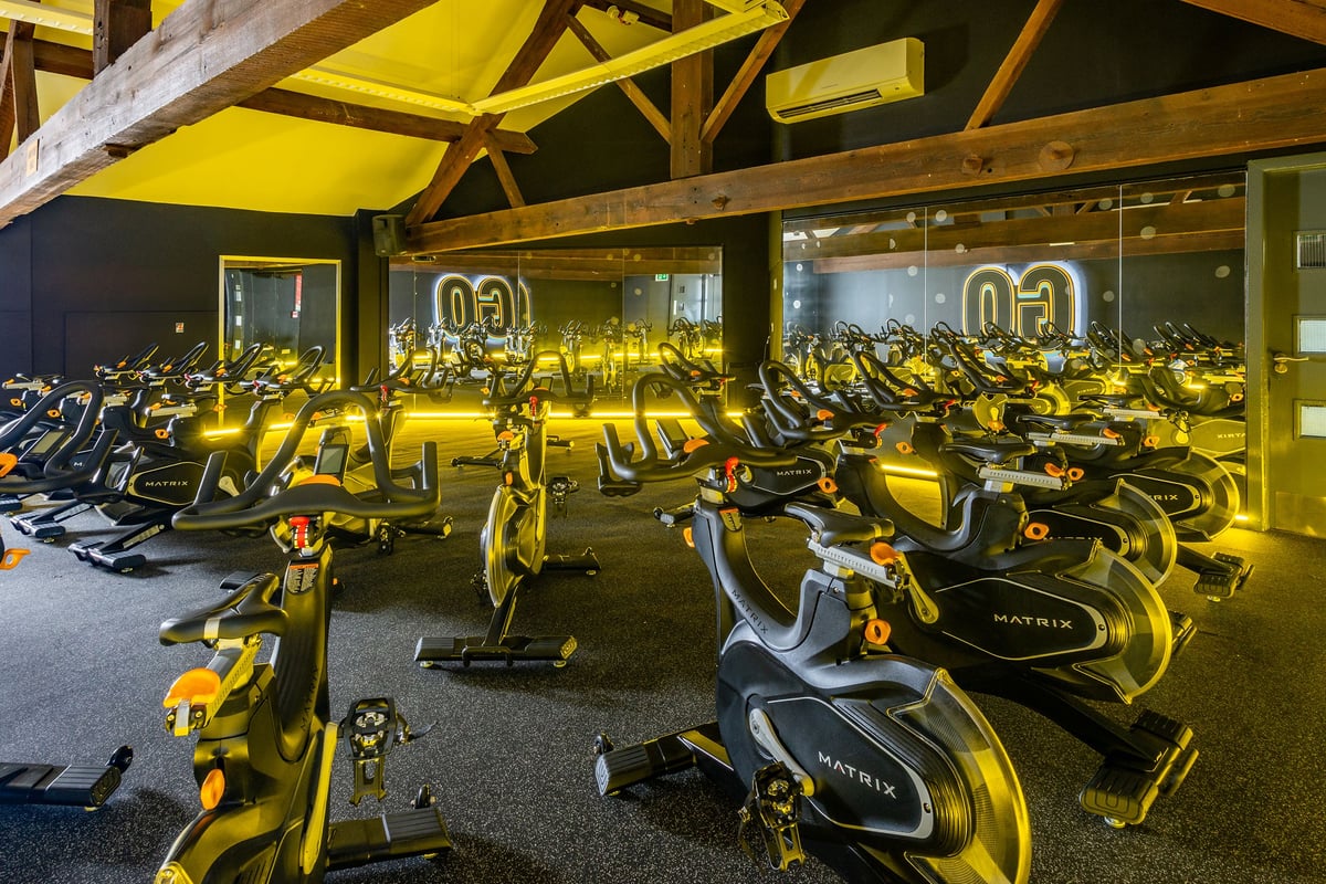 PureGym Northwich: Rows of yellow stationary bikes under wooden beams and yellow canopies.