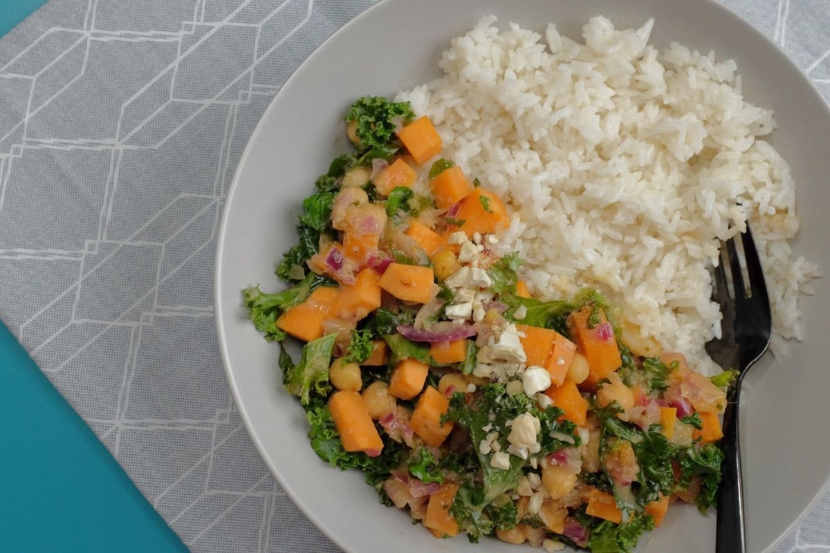 Bowl of white rice beside mixed vegetables with kale, sweet potato and chickpeas