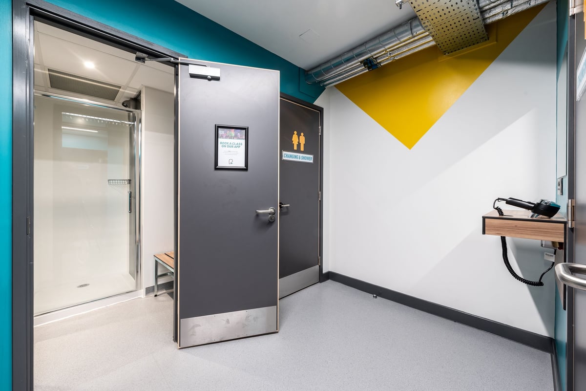 PureGym London Welling: Entrance area with stainless steel fridges, grey door, vivid teal and yellow wall graphics.