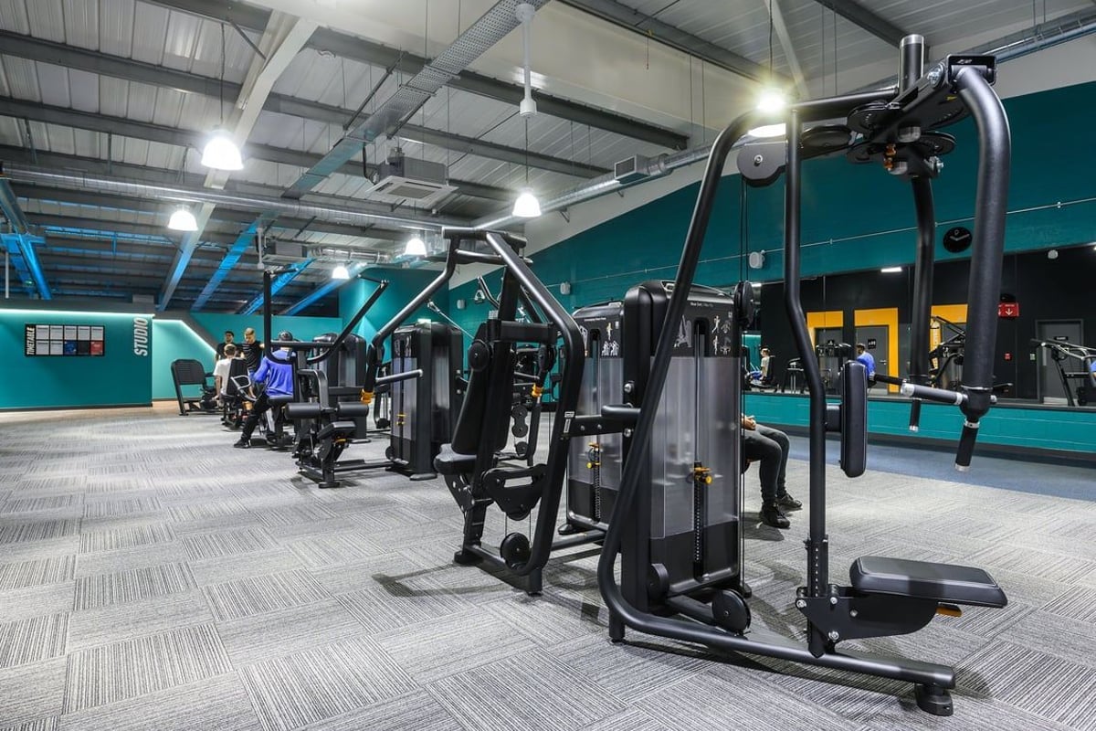 PureGym Bristol Abbey Wood Retail Park: Fitness studio with rows of weight machines, benches, and rubberized flooring.