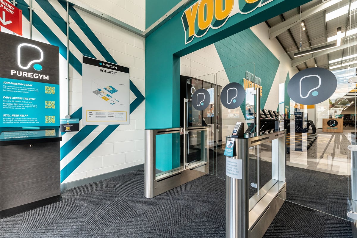 PureGym Chippenham: Resistance machines, treadmills, and self-service kiosks behind glass doors.