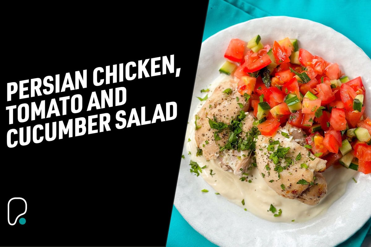 Grilled chicken with chopped tomato and cucumber salad on a white plate with sauce