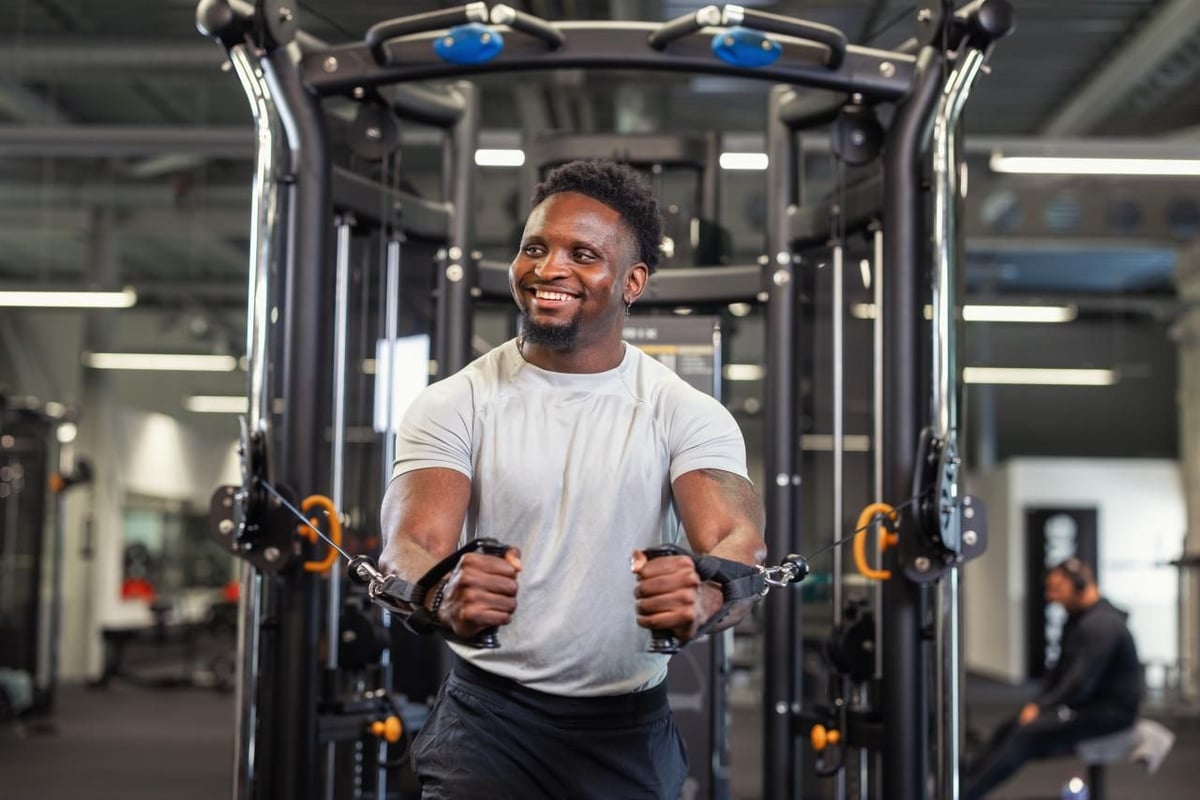 A smiling PureGym member using the functional trainer machine