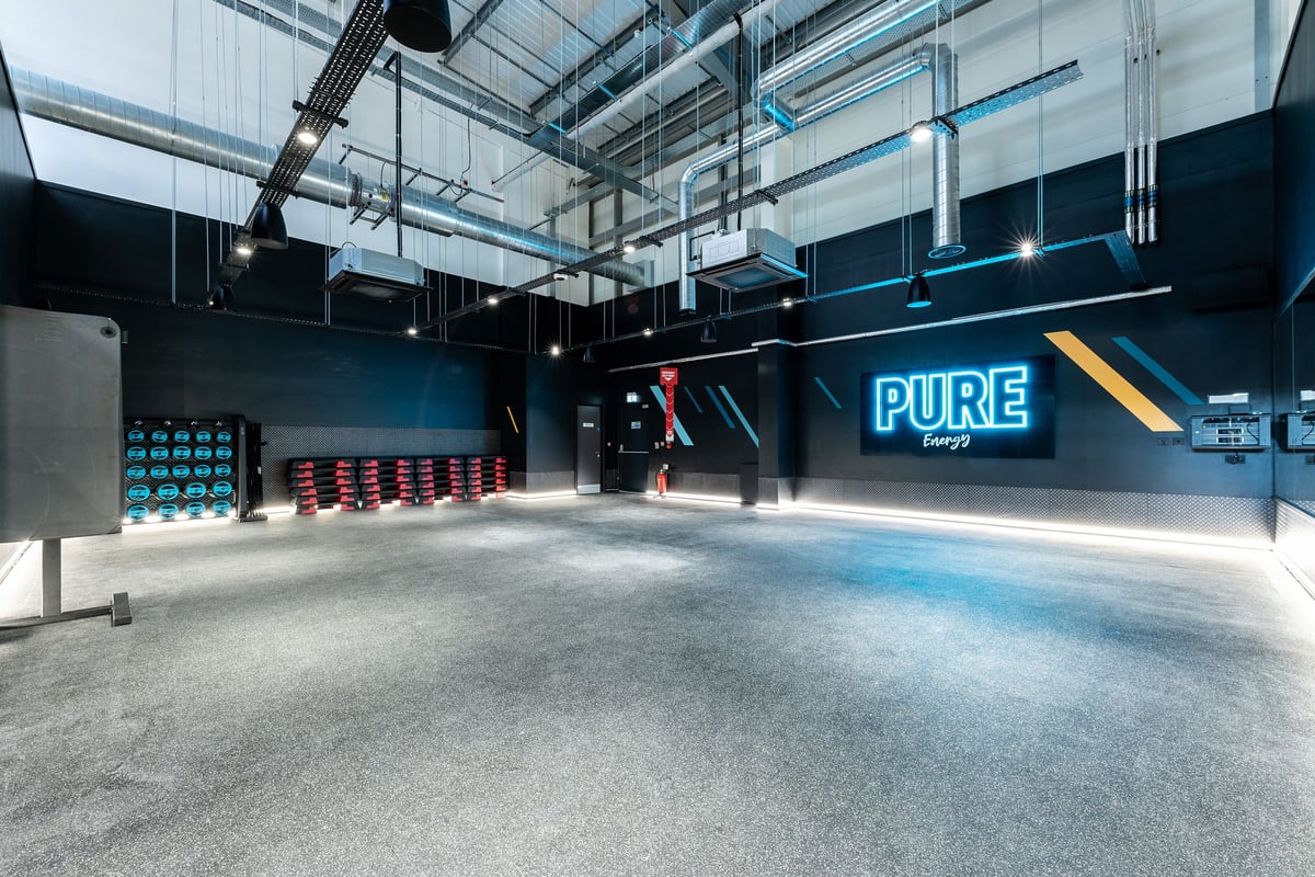 PureGym Kirkby: Strength training area with wall-mounted rigs, lifting platforms, weightlifting equipment.