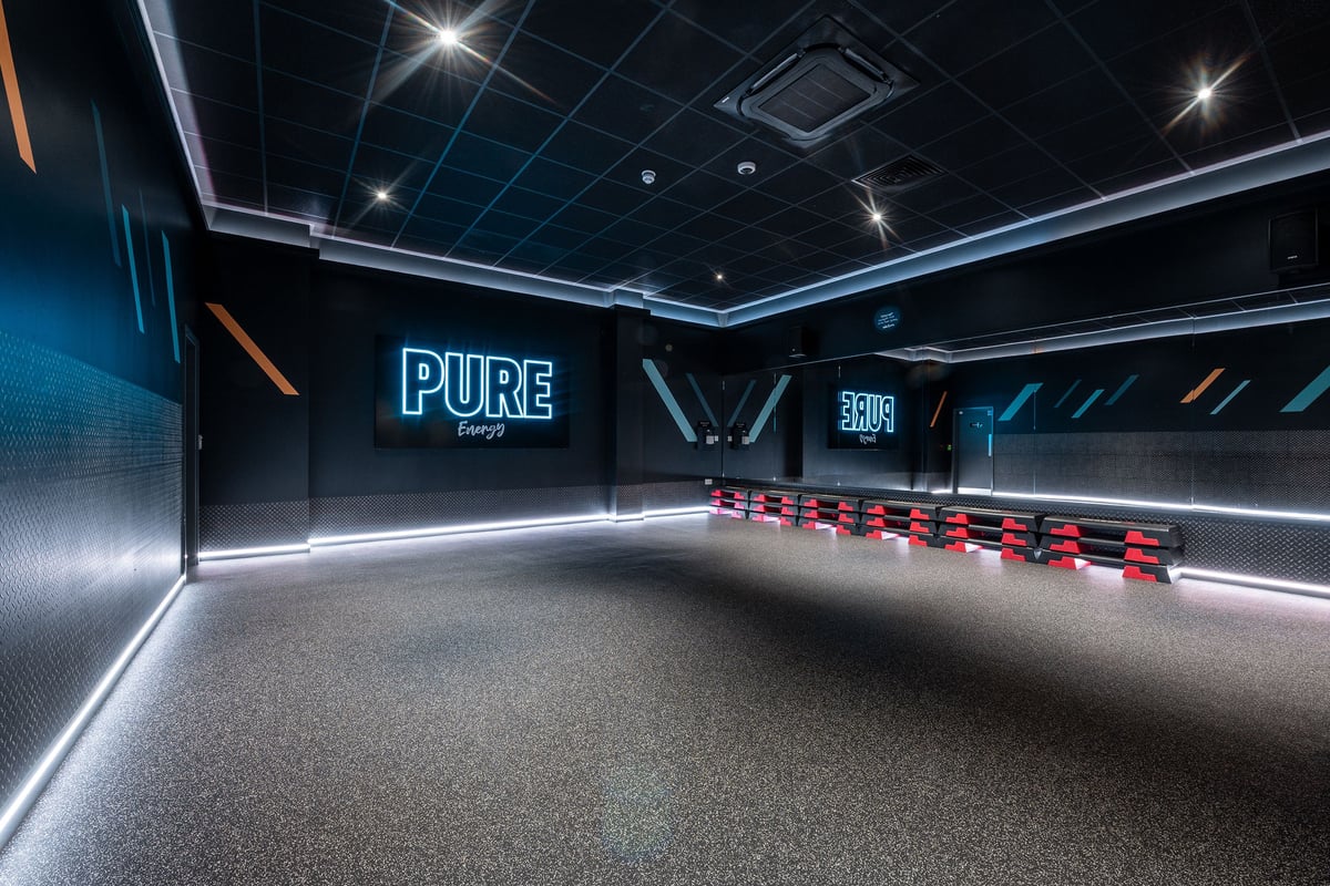 PureGym Weston-super-mare: Red seats in a dark corridor with PURE energy branding on the wall.