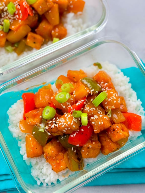 Sweet and sour tofu with red and green peppers, spring onions, and sesame seeds on rice