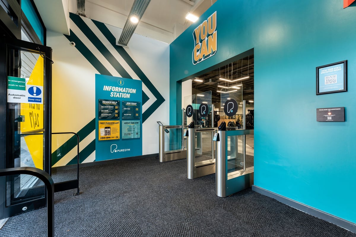 PureGym Lincoln Carlton Centre: Information station, turnstiles, and directional signage at gym entrance.