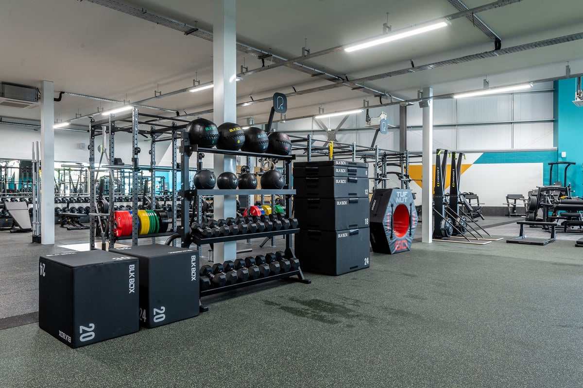 PureGym Nottingham West Bridgford: Gym interior with weight racks, medicine balls, resistance bands, and rubberized floors.