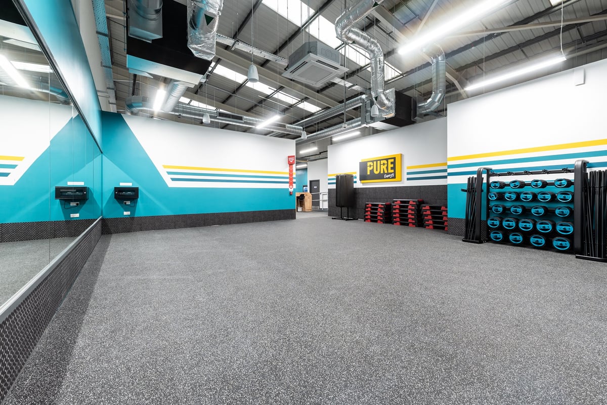 PureGym Newhaven: Rubberized floor, weight plates, punching bags, and resistance machines in a vibrant studio.