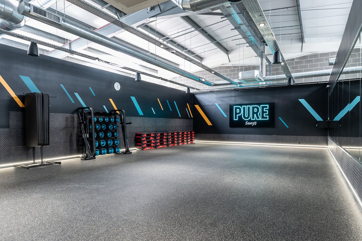PureGym Sittingbourne: Black studio with colourful freeweights, benches, mirrors, and branded fitness equipment.