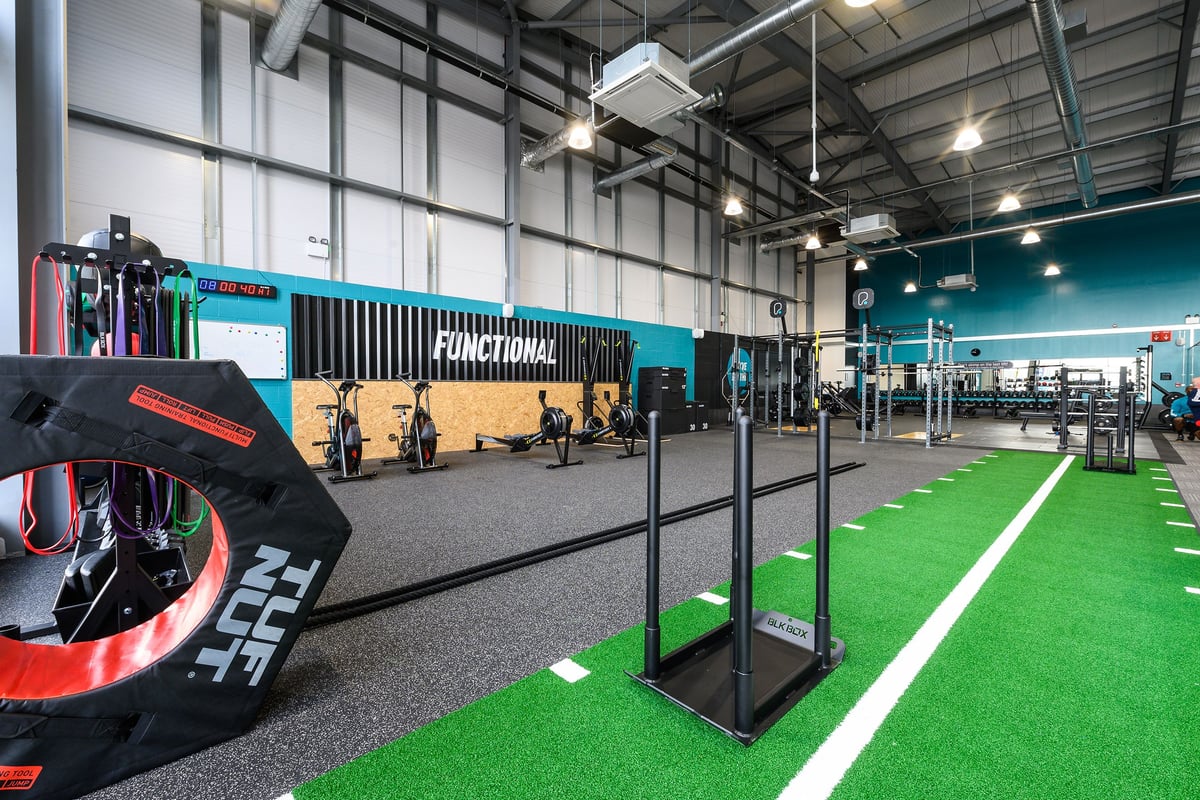 PureGym Maldon Blackwater Retail Park: Functional training area with turf, squat racks, weight plates, rubberized flooring.