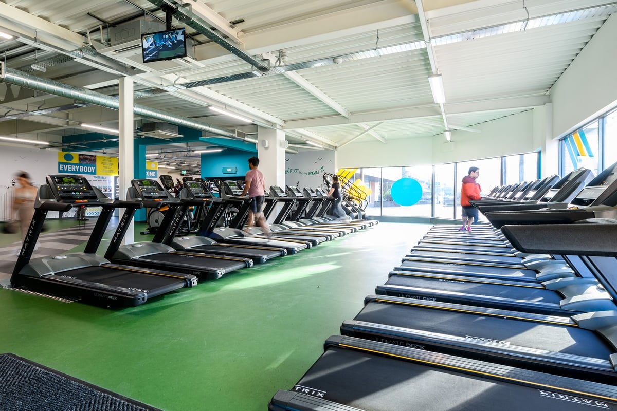 PureGym Telford: Rows of treadmills, fitness screens, open layout with artificial turf flooring.