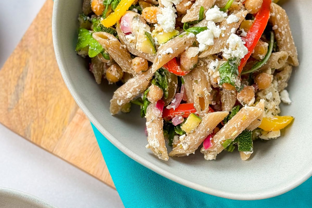 Whole wheat penne pasta salad with chickpeas, feta, and mixed vegetables in bowls