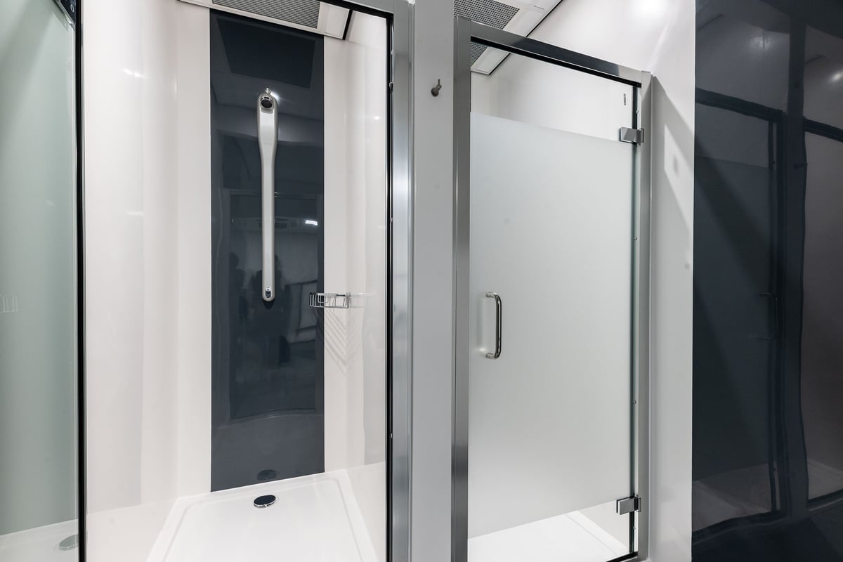 PureGym Glasgow Milngavie: Shower rooms with glass doors, tiled floors, and grab bars.