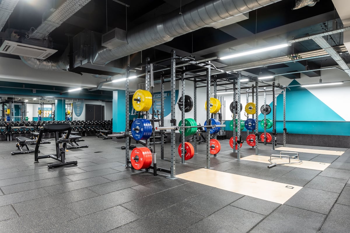 PureGym London Ilford: Weight racks, benches, colourful weight plates, rubberized flooring in a gym environment.