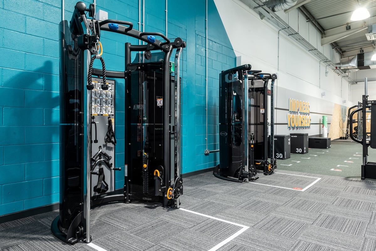 PureGym Stockport North: Black functional training rigs, rubberized flooring, exposed brick walls, industrial aesthetic.