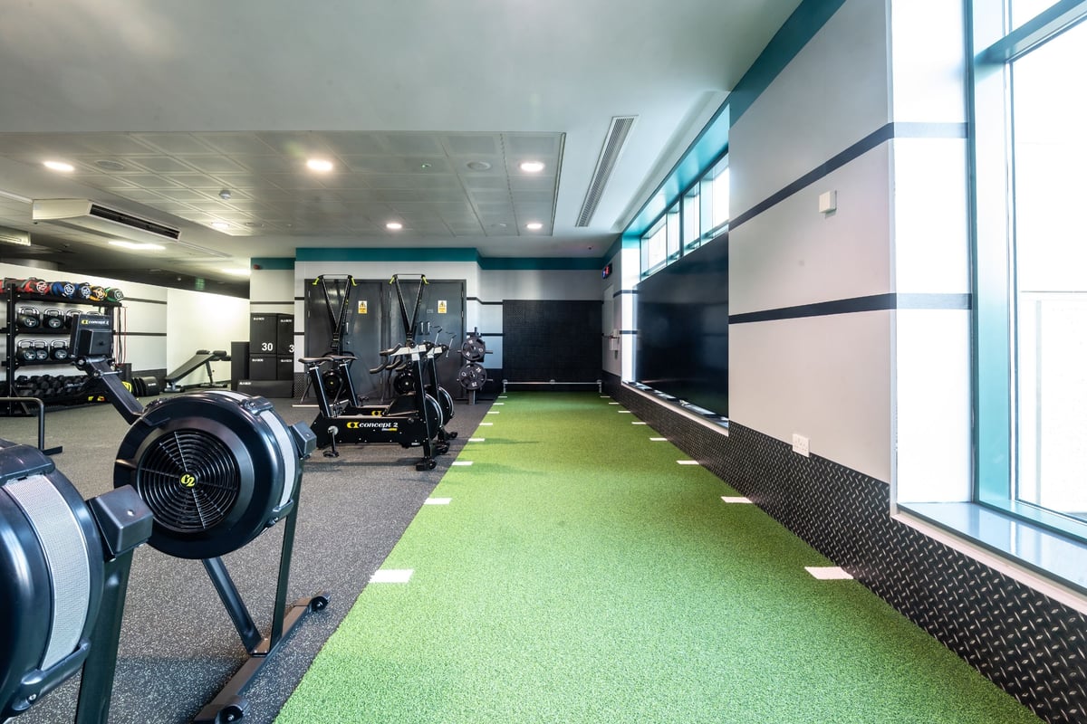 PureGym Edinburgh Exchange Crescent: Free weights, weight machines, green turf area, mirrored wall in a modern gym setting.