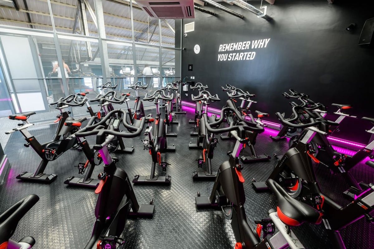 PureGym London Clapham: Rows of spin bikes in black, pink and red colours with a motivational wall text.