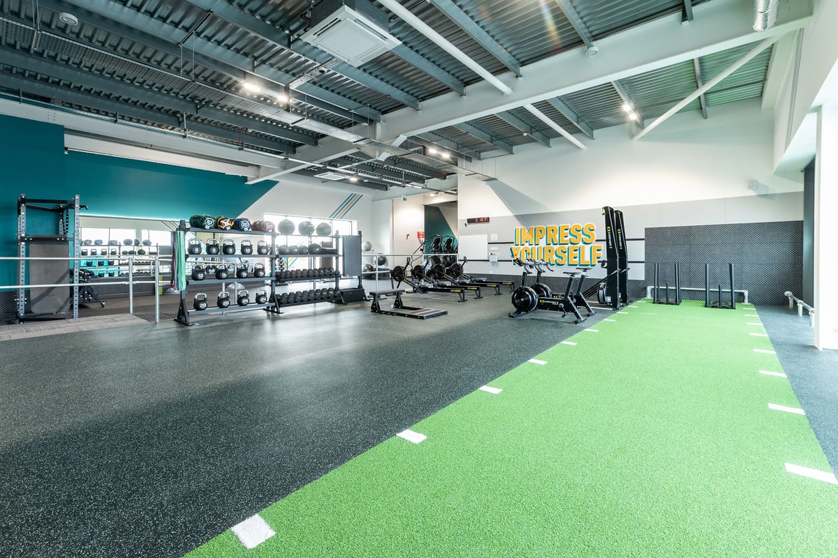 PureGym Bicester: Resistance machines, dumbbell racks, weight benches, rubberized flooring, and green turf area.