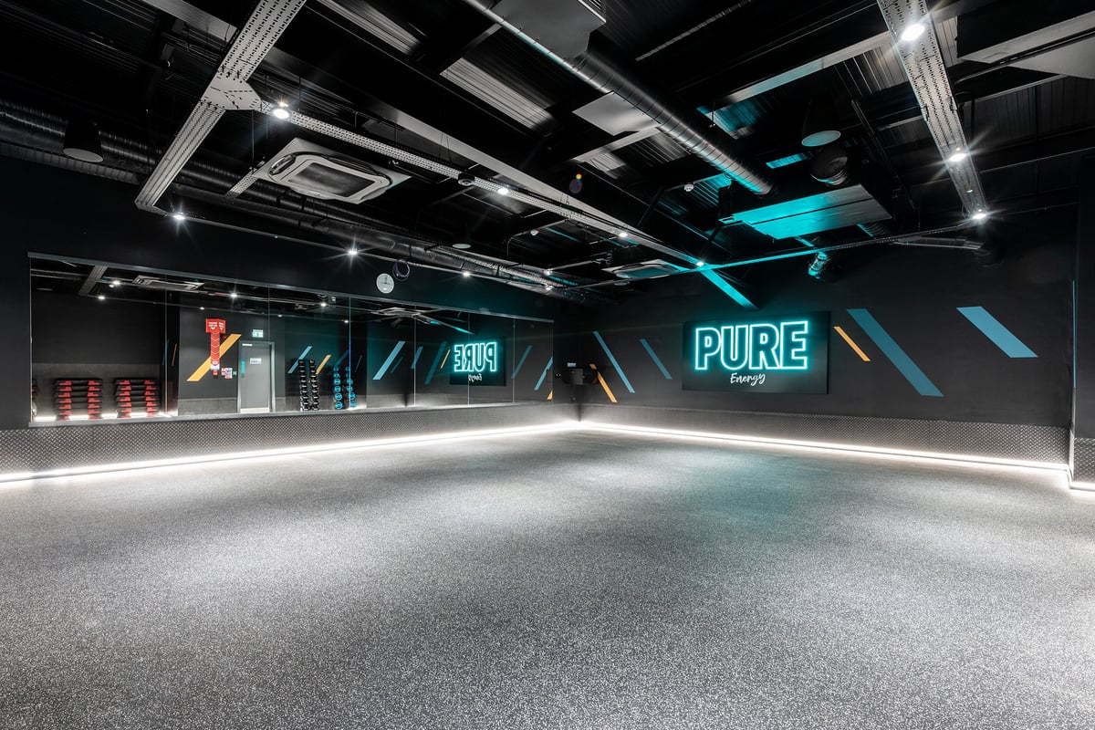 PureGym Ormskirk: Futuristic gym studio with neon lights, open floor space, and branded signage.