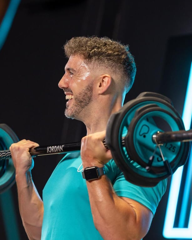 Konzentrierter Mann hebt Langhantel mit Intensität in moderner Fitness-Umgebung mit blauer Beleuchtung